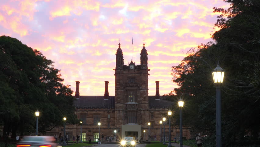 Historic sandstone university building in Sydney at sunset, time lapse of orange clouds over heritage campus architecture 