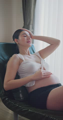 Tired pregnant woman suffering from a headache and fatigue at home.