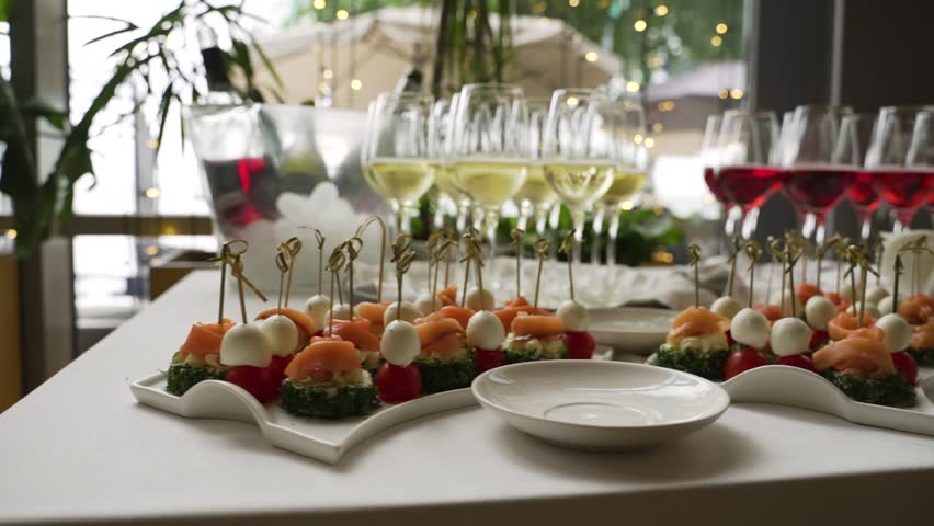 Catering in the banquet hall. Table set with vegetable, fish, and cheese appetizers and glasses of wine and champagne at wedding reception.