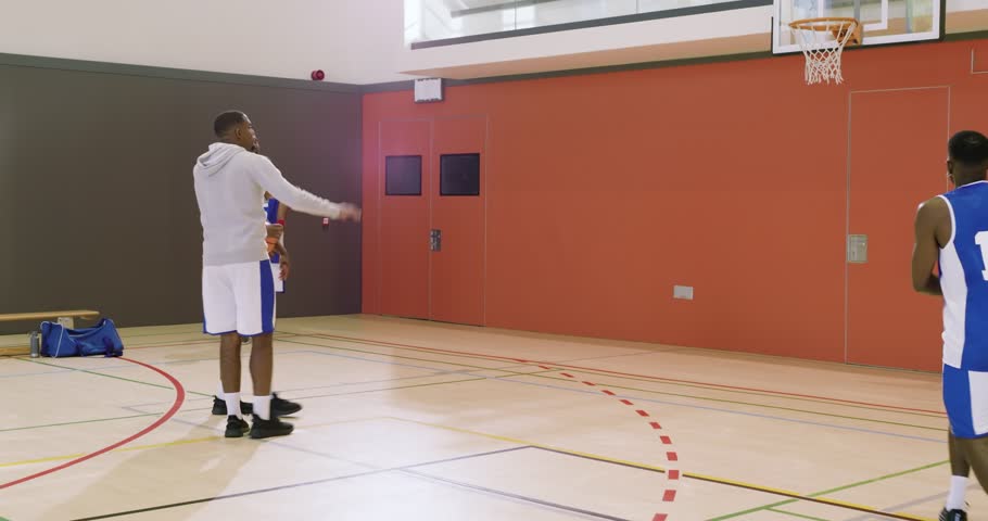 African American coach signaling player #12 jogging baseline and shooting ball while timing. Athlete, training, focus, sport, coaching, fitness, teamwork