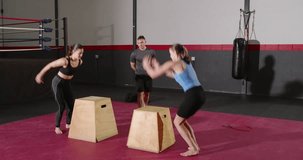 Male coach signalling female trainees alternating box jumping with red timer for fitness training. Athleticism, strength, agility, determination, discipline, training, motivation - Powered by Shutterstock - Get 15% off with code: PIKWIZARD15
