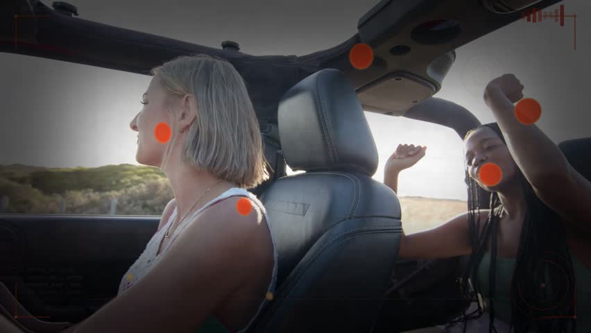 Driver driving convertible, passenger tapping driver, causing travel nodes and sun flaring. Women, car, coast, seaside, opentop, backlit, silhouette