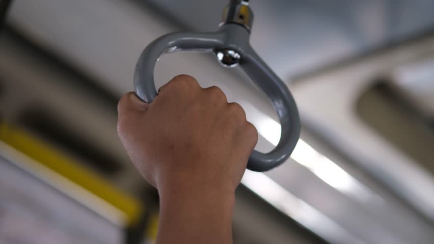 Hand grips a subway handle. Soft lighting glows behind.