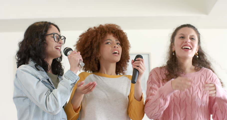 Diverse female friends responding to left mic raise, singing lead backup harmonies in living room. Musicians, vocalists, performance, ensemble, harmony, celebration, entertainment