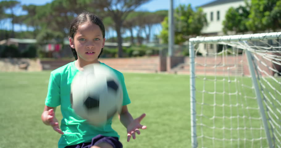 African American child in green tee receiving soccer ball, tossing, juggling, practicing by goal. Athlete, preteen, outdoor, field, grass, sunny, vibrant