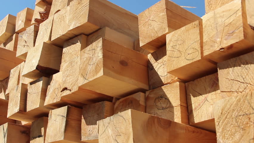 Stack of square wooden chips at construction yard. Dolly pan shot, blue sky