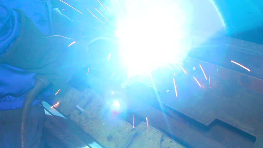 Welding process as man in helmet lights up weld torch
