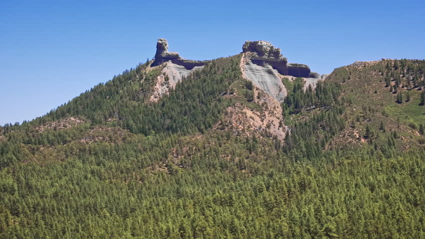 70mm cinematic aerial drone shot of Chimney Rock near Owl Creek Pass in Uncompahgre National Forest, near Pagosa Springs, Colorado, framed by rugged alpine terrain and jagged peaks.
