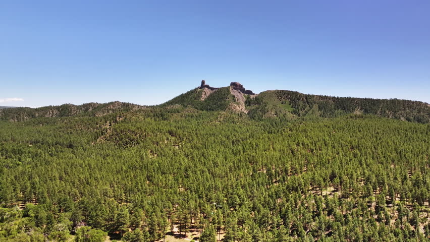 70mm cinematic aerial drone shot of Chimney Rock near Owl Creek Pass in Uncompahgre National Forest, near Pagosa Springs, Colorado, framed by rugged alpine terrain and jagged peaks.