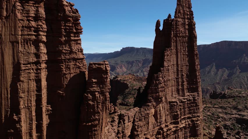 Fisher Towers showcasing dramatic red Cutler sandstone formations under a clear blue sky. Aeriel, Pullback Shot
