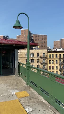 Pan shot of the "125 Street" subway station sign on the elevated platform in Harlem, New York City