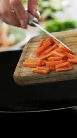 Girl Adding Chopped Carrot Into Hot Steaming Wok Pan Cooking Asian Wok Food In Kitchen, Vertical Video