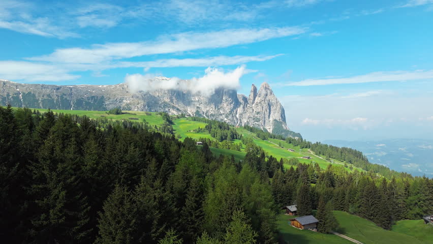 Dolomites mountain range and alpine landscape of Alpe di Siusi, South Tyrol, Italy. Wide aerial view of forest, meadows and rocky peaks