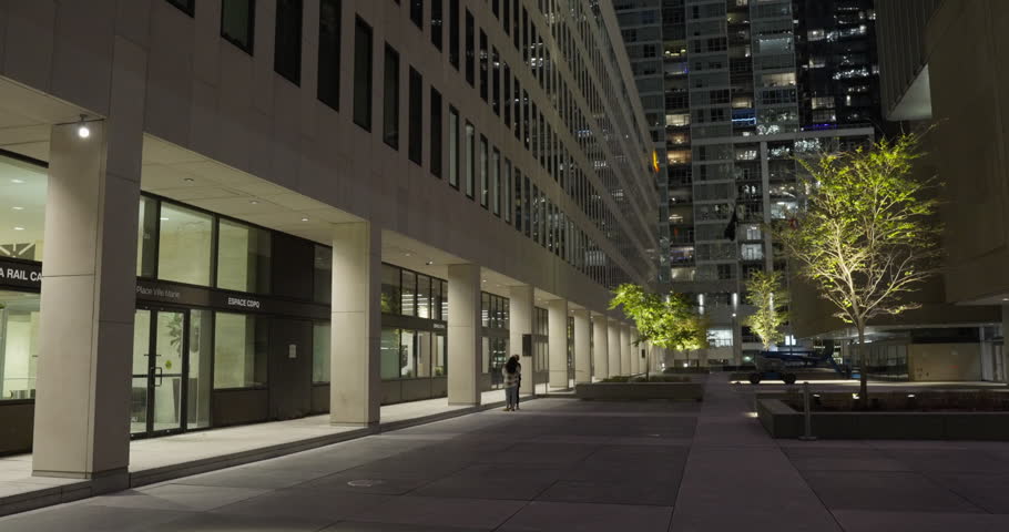 People At Urban Plaza Surrounded By Modern Office Buildings At Night In Montreal, Canada. wide shot