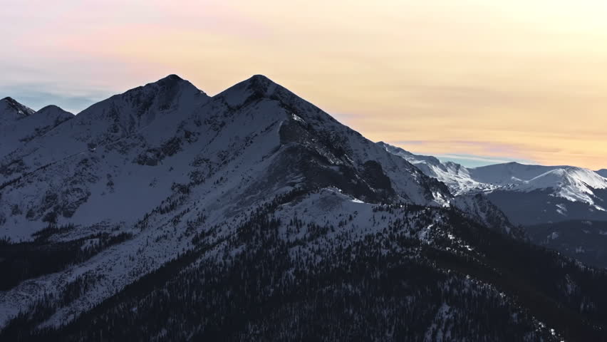 A cinematic, high-flying 70mm-style aerial drone shot of snowy peaks surrounding Dillon and Frisco near Breckenridge in Colorado