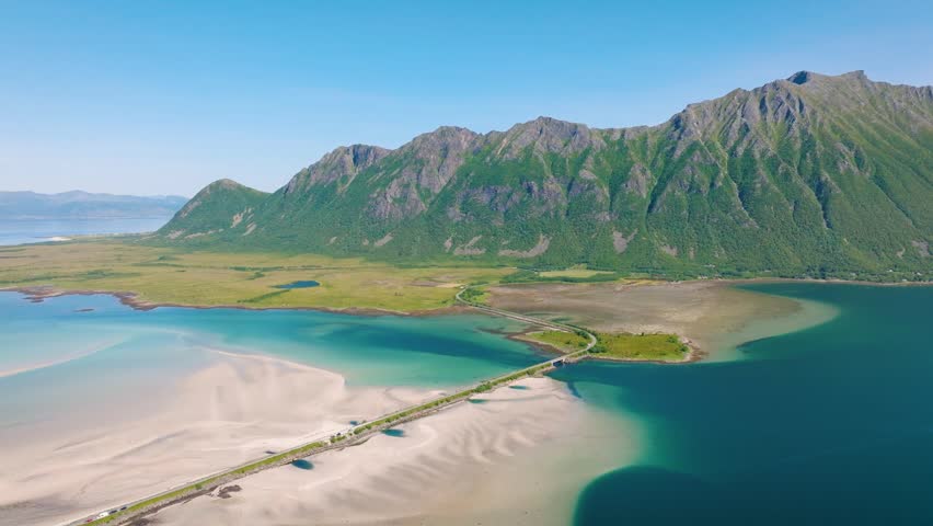 Northern landscape with road, crystal clear water and white sand. Scenic summer arctic landscape with mountains, fjords and northern nature in Norway. Travel and adventure in Scandinavia.