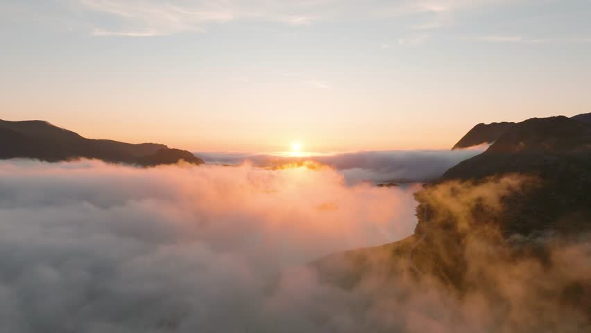 Aerial drone video of sunset over Lofoten mountains and fjords in Norway. Midnight sun landscape with arctic fog, moody clouds and scenic summer nature from above.