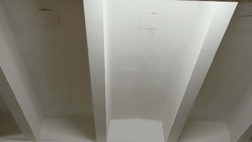 Subtle motion across a minimalist interior ceiling featuring exposed structural beams and recessed coffers, emphasizing painted textures, shadow gradients, and geometric lines