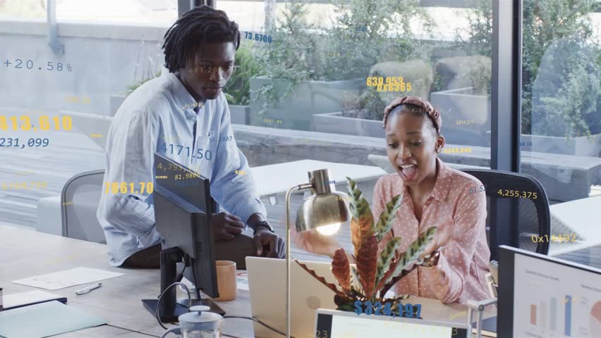 Charts appearing, pink-blouse woman and blue-shirt man at office pointing at laptop, reviewing data. Collaboration, teamwork, professionals, office, workspace, dashboards, analytics