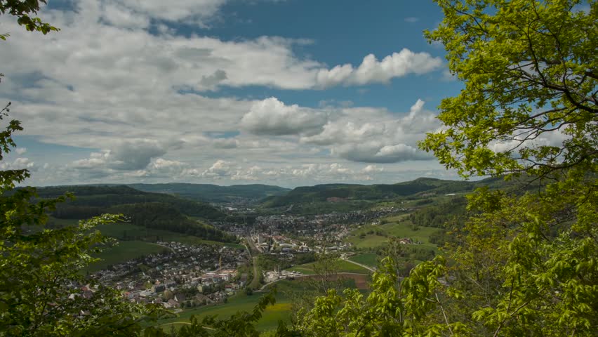 Panoramic High-Angle View of a Small Town Nestled in a Lush Green Valley Under a Blue Sky