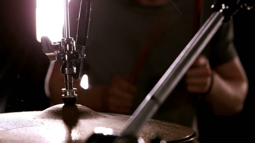 Drummer striking cymbal on music kit, mic passing, white teal icons syncing with beats for creators. Percussionist, drums, backlight, studio, moody, motionblur, microphone