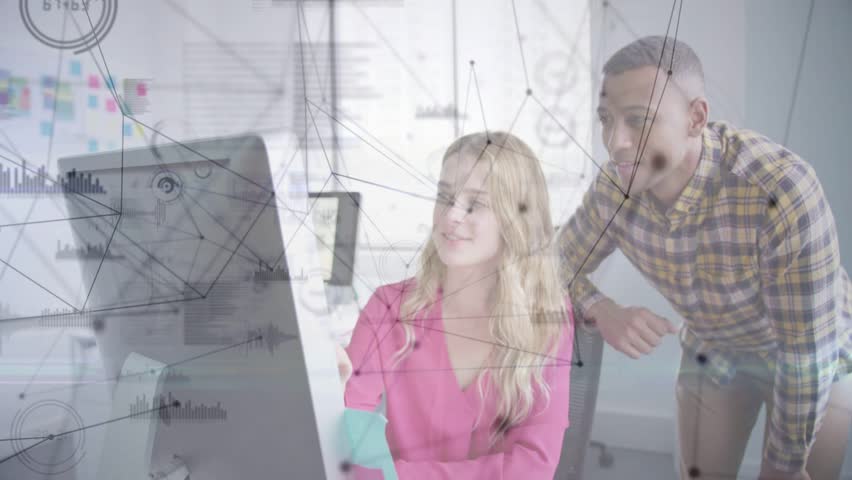 Seated woman clicking at monitor, man leaning and pointing, both reviewing on-screen design graphs. Collaboration, teamwork, visualization, analytics, prototyping, interface, office