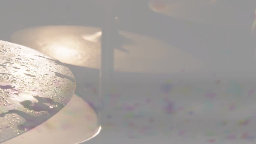 Near cymbal vibrating from backlight flare, droplets shifting, banding showing texture for music. Percussion, metal, grooved, shimmer, reflections, closeup, stage