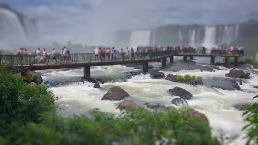 Crowd of tourists watch powerful Iguazu waterfall with strong water flow