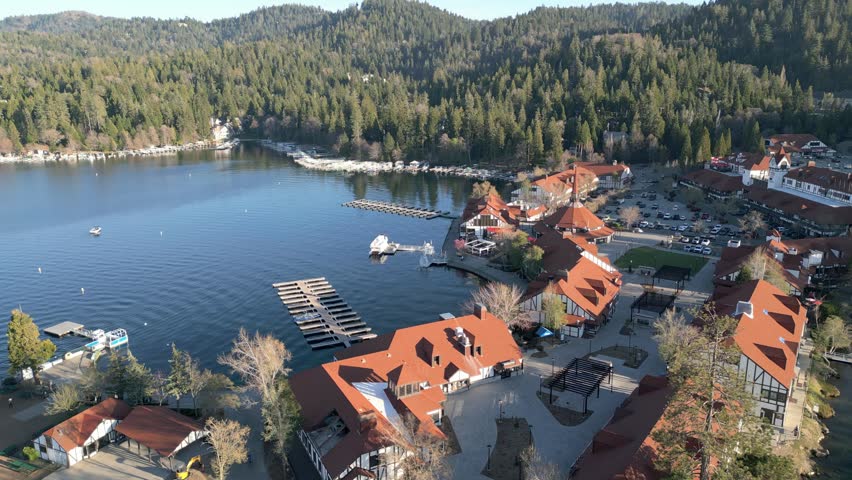 Aerial drone footage of Lake Arrowhead Village marina with docks, waterfront buildings and forest. Aerial video of Lake Arrowhead Village showing marina docks, waterfront buildings and surrounding pine forest. Suitable for travel, tourism and real estate footage.