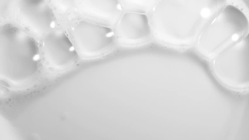 Foam bubbles background. Moving Soap foam popping bubble, white backdrop. Soap sud macro structure. Soap foam close-up. Clean, cleaning concept, laundry, shower. Slow motion 