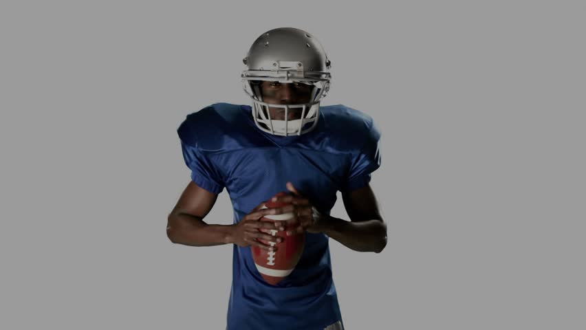 Footballer stepping center, fixing helmet, holding ball, adopting snap pose, HUD mirroring motion. Athlete, headgear, pads, leather, blue, silver, overlay