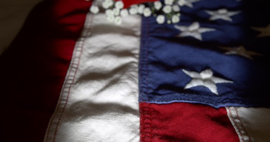 Slow motion panning across a US American flag with a single red rose. For Memorial Day, Veteran