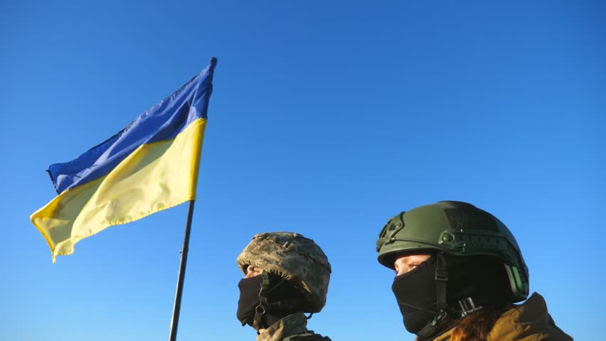 Young Ukrainian soldiers standing on hilltop raising national flag, holding hands in unity, symbolizing support, courage, and wartime victory.