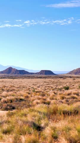  arid desert landscape with mountains under blue sky, dry grass prairie in wilderness, scenic western american or mediterranean desert view.