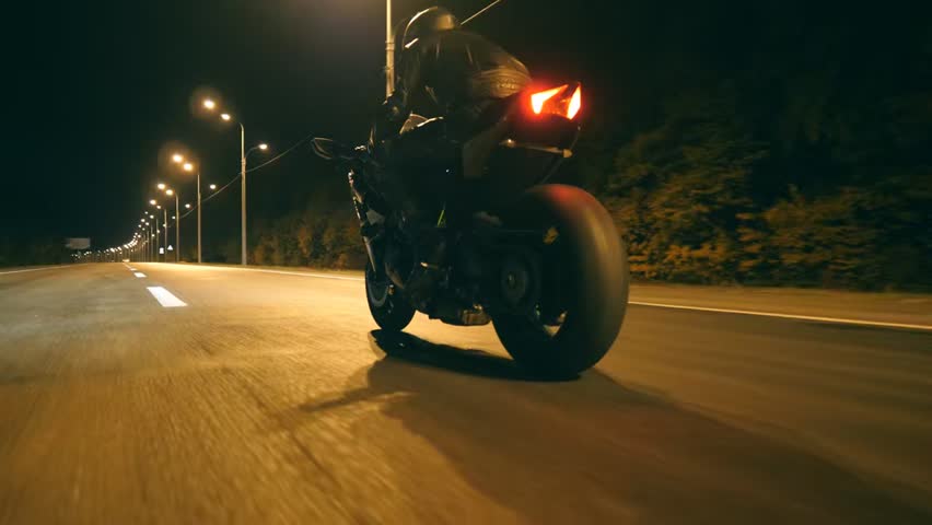 Man riding a sport motorbike at high speed on empty city streets at night, capturing freedom, adrenaline, and adventure in dynamic low-angle view.