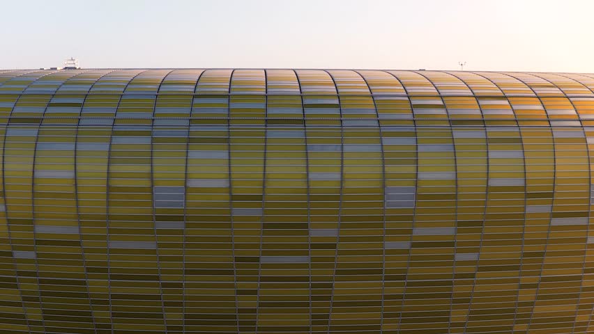 Aerial footage revealing the modern polsat plus arena stadium in gdansk, poland, with the city skyline and the baltic sea in the background