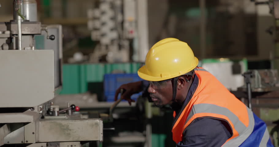 A technician performs precision grinding and close inspection on a metal component in a manufacturing facility, showing finishing work, process control, and industrial supervision.
