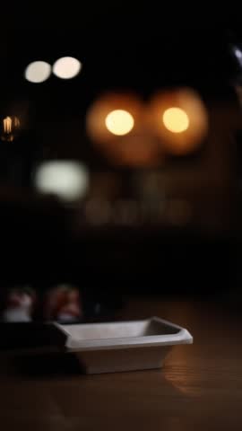 Vertical screen soy sauce being poured into dipping bowl close up asian cuisine condiment serving minimal composition restaurant table food detail