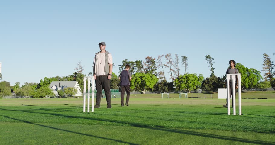 Diverse cricket players on pitch running in, bowling, leaping to catch ball, and clapping for drill. Athletics, teamwork, outdoor, competitive, fitness, recreation, sportsmanship