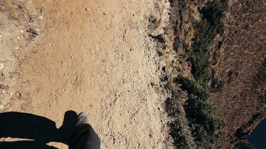 POV trekking in Himalayas, Nepal. First person view of walking feet on mountain trail with stunning valley and snowy peaks on the way to Everest Base Camp