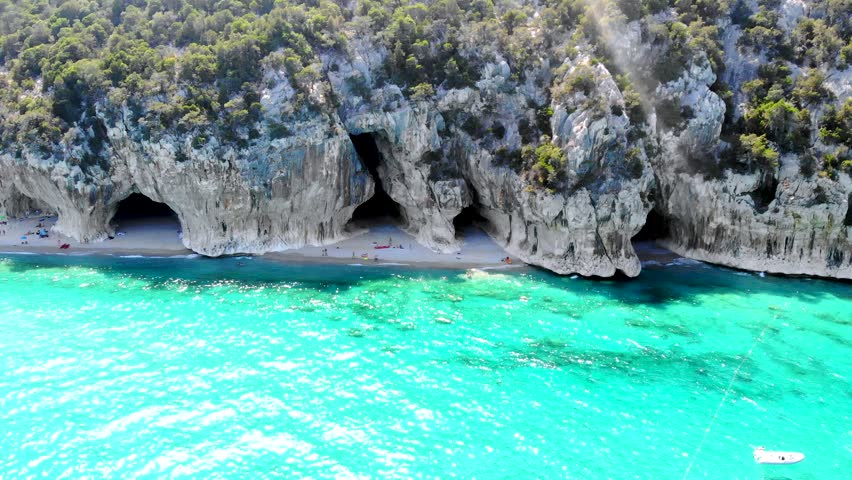 Explore the stunning Cala Luna beach in Sardinia, Italy, where turquoise waters meet dramatic cliffs. Relax on the sandy shores and enjoy the breathtaking scenery all around.