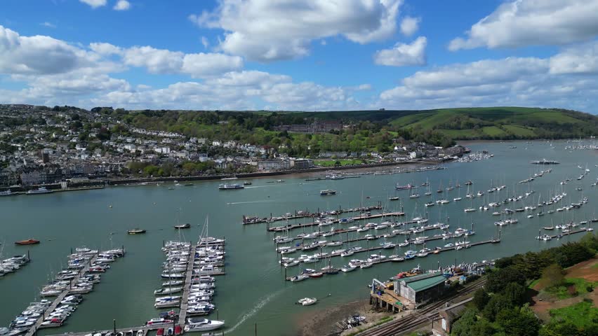Dartmouth, River Dart, South Devon, England: DRONE VIEWS: The drone flies over yachts and boats moored at Darthaven Marina continuing on to show a passenger ferry sailing downriver and the Higher Ferry (mid-right of picture) crossing towards Dartmouth. 
Dartmouth is a port town and set on the western bank of the River Dart. The Dart is a tidal drowned river (rea or ria) that runs inland as far as Totnes and lies within the South Devon Area of Outstanding Natural Beauty and South Hams district. 
