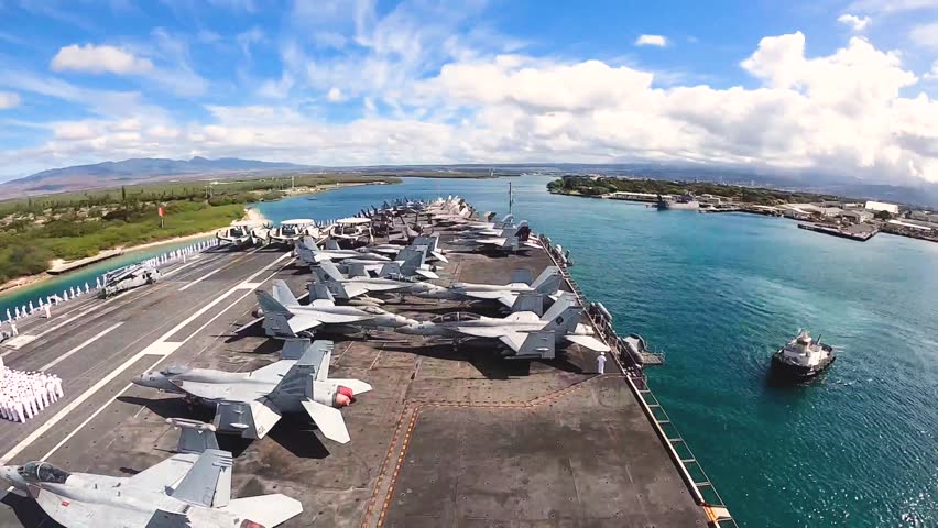 An aerial view of the USS Nimitz (CVN 68) aircraft carrier in Pearl Harbor, Hawaii, with sailors and aircraft lined up on the flight deck for a change of command ceremony.