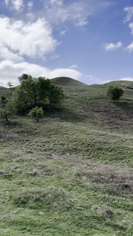 Scenic panoramic view of hiking trail to the Mam Tor ridge with a winding hiking trail and dramatic green hills under a bright blue sky with clouds. Peak Disctrict, England, UK.