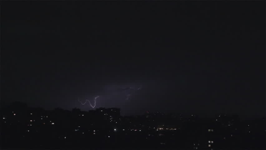 Lightning strikes buildings in city sky. Thunder roars with sound