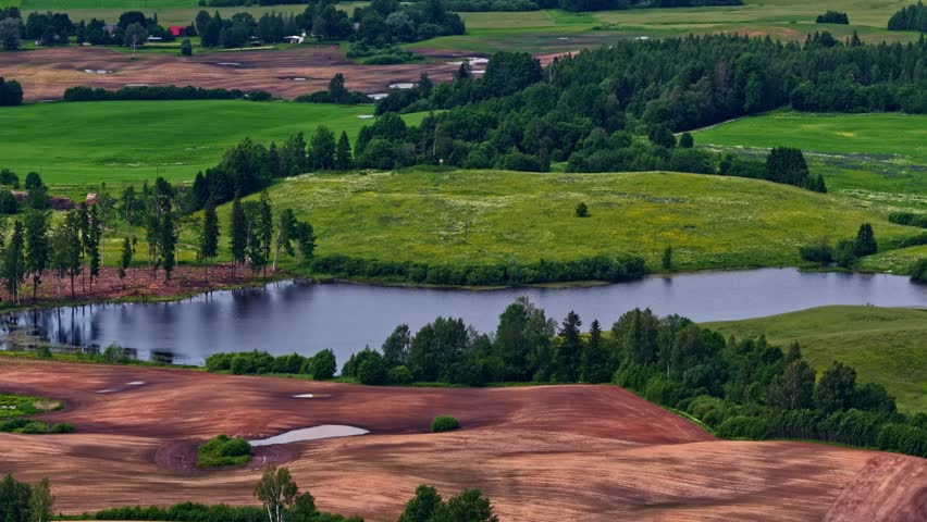 A smooth vertical drone descent revealing a serene lake nestled between lush green and brown hills.