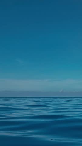 Calm blue water meets distant horizon, infinityedge pool illusion blending with ocean, gentle ripples across glassy surface, soft sunrise gradient, panoramic resort vista evoking, vertical video