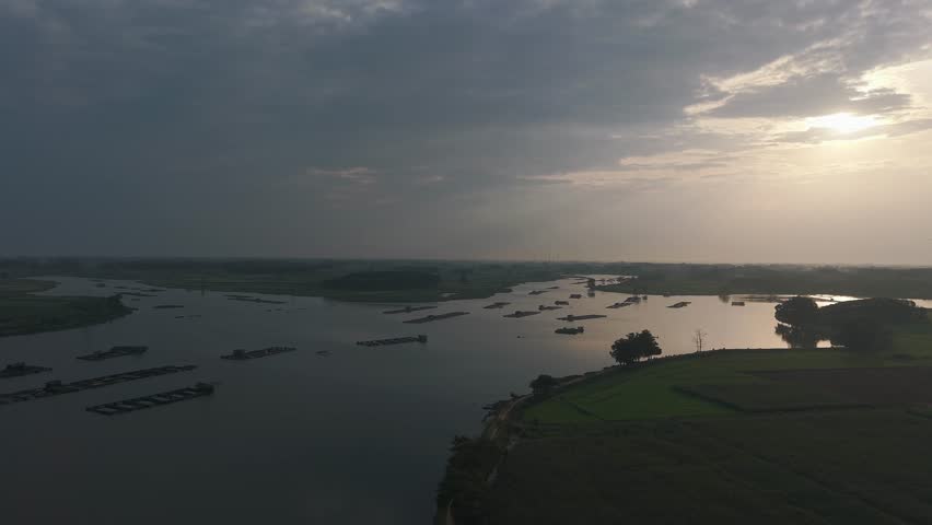 A serene river landscape with dramatic clouds at sunset, featuring small islands and a peaceful atmosphere.