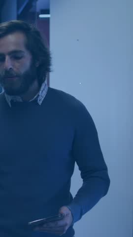 Bearded man entering open-office, tapping phone and causing overlay expanding, showing user links. Office, networking, digital, connectivity, glass, workspace, vertical video