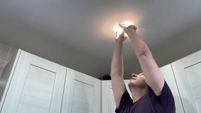 Person changing kitchen ceiling bulb. Homeowner replacing and testing kitchen ceiling lighting fixture. Person performing do it yourself task to update kitchen ceiling illumination and socket - Powered by Shutterstock - Get 15% off with code: PIKWIZARD15